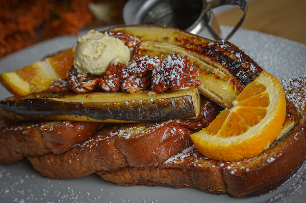 Banana pecan French toast from Hash House A Go Go, topped with caramelized bananas, candied pecans, and whipped butter—an indulgent favorite among locals.