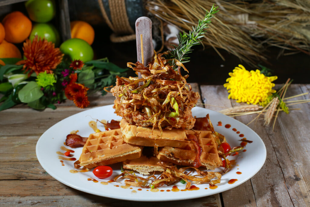Culinary icon at Hash House A Go Go—Sage Fried Chicken & Waffle Tower stacked high with crispy leeks, bacon, and a rosemary garnish, beloved by locals in Henderson.