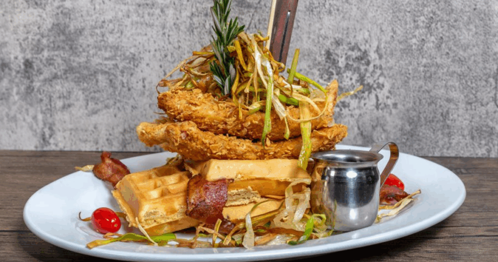 Chef-crafted fried chicken and waffles at Hash House A Go Go Henderson with rosemary garnish and signature presentation